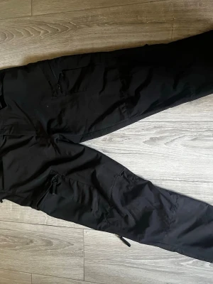 Friluftsbyxa - Vandringsbyxor outdoor byxa. Bra skick. Dragkedjor vid benfickor och ställbart vid vrist. Skulle säga att passformen är mellan L och xl. Dem passar bra på mig och jag brukar köpa byxor och jeans i 34/32