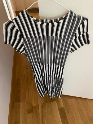 Tiger of Sweden klänning  - Säljer en svartvit randig kortklänning med rund hals och korta ärmar. Klänningen har en snygg öppen ryggdetalj och är gjord i ett mjukt, lätt material som passar perfekt till sommaren. Supersnygg till sneakers eller sandaler!
