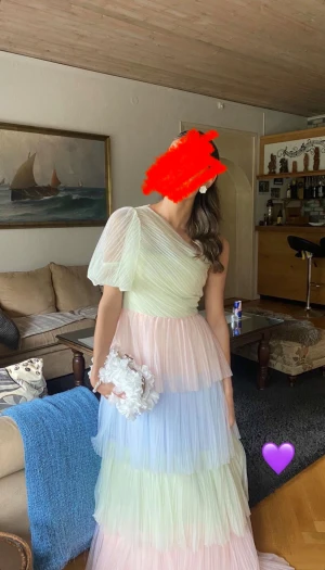 Pastellfärgad oneshoulder långklänning - Säljer en magisk långklänning i flera lager pastellfärgad tyll. Klänningen har oneshoulder-design med puffärm och volanger i ljusgrönt, ljusblått och ljusrosa. Perfekt för dig som vill sticka ut på bal eller fest! 💜