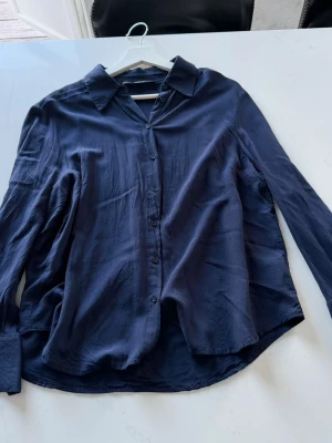 Mörkblå silkeslik skjorta - Gina Tricot Skjorta – Marinblå strl L ✅ Märke: Gina Tricot ✅ Storlek: L ✅ Färg: Marinblå ✅ Detaljer: Vida muddar, klassisk krage, knäppning framtill ✅ Skick: Begagnad, gott skick ⚠️ Obs: Något skrynklig på bilderna – försvinner enkelt med en strykning! ✅ Pris: 159 kr (frakt tillkommer) Frågor? Skriv gärna! 📦