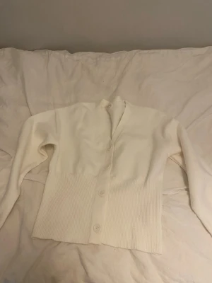 Vit ribbstickad kofta med knappar - Den är en tajt modell. Gammal modell från Zara. Dock inte använd särskilt mkt.