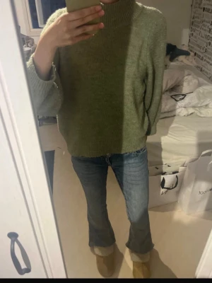 Olivgrön stickad polotröja - Mysig olivgrön stickad polotröja med avslappnad passform och breda trekvarts ärmar. Lite nopprig men man tänker inte på det!