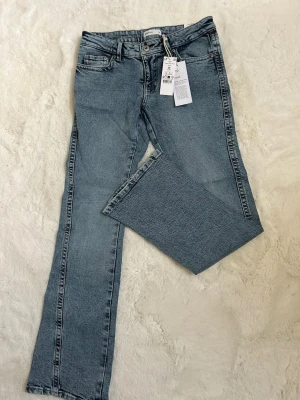 Blå bootcut jeans från Gina tricot  - Snygga blå bootcut jeans från Gina i modellen Twisted Bootcut. Jeansen har klassisk femficksdesign, låg midja och raka ben med lätt utsvängning. Tillverkade i denim med en autentisk tvättad look. Perfekta för en trendig och avslappnad stil.