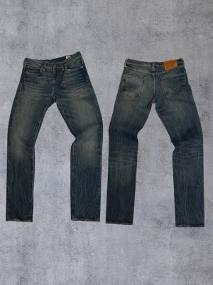 Feta Levi's 511 med sjuk tvätt - Säljer ett par Levi's 511 jeans i klassisk blå denim. Jeansen har fem fickor, dragkedjegylf och snygga slitningar för en cool look. Perfekta för dig som gillar en smal passform och tidlös stil.