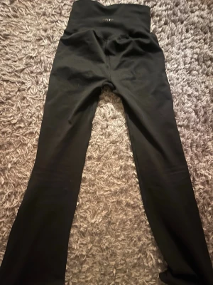 Svarta bootcut träningsbyxor - Säljer ett par svarta träningstights med bootcut-modell och hög midja (jag brukar vika ner midjan för lågmidjade passform). Finns delvis scrunch. De är stretchiga och sitter tight upptill men har utsvängda ben.