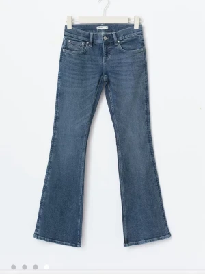Blå bootcut jeans från Gina tricot  - Snygga blå bootcut jeans från Gina tricot  med klassisk femficksdesign och unika vita broderier på bakfickorna. Jeansen har medelhög midja och är tillverkade i stretchig denim för en bekväm passform.