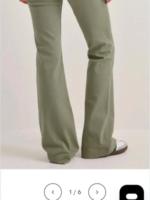 Olivgröna bootcut byxor - Snygga olivgröna byxor med bootcut-modell och hög midja. Byxorna har en avslappnad passform och är tillverkade i ett mjukt bomullsmaterial. Perfekta för dig som gillar en retroinspirerad look.