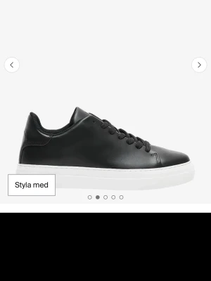 Svarta sneakers i skinn från Selected - Stilrena svarta sneakers från Selected med klassisk låg profil och vita sulor. Skorna har snörning och är tillverkade i slätt skinn för en clean look som passar till allt. Perfekta för dig som gillar minimalistisk och tidlös stil.