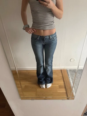 Blå bootcut jeans med låg midja - Säljer ett par blå bootcut jeans med låg midja och klassisk femficksdesign. Jeansen har en snygg tvättad look. Skulle säga xs/s!