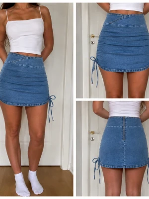 Blå kort jeanskjol med snörning - Ny & aldrig använd. Säljer en ljusblå kort jeanskjol med snörning längs sidorna och dragkedja bak. Kjolen har en tight passform och är gjord i mjukt denimtyg. Perfekt för dig som gillar en trendig och avslappnad stil. Midje storlek: 72 
