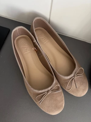 Beige ballerinaskor med rosett - ALDRIG ANVÄNDA! Säljer då dom är lite små för mig som vanligtvis har 38-39. Snygga beige ballerinaskor från 157 med rund tå och dekorativ rosett framtill. Skorna har en mjuk ovandel i mockaimitation och en klassisk, stilren design som passar till många outfits. 
