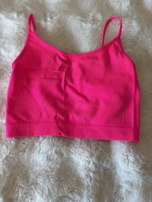 Rosa ribbad crop linne  med smala band - Säljer en snygg och enkel rosa ribbad crop linne  med smala axelband. Materialet är mjukt och följsamt för extra komfort.
