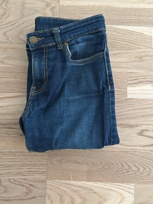 Blå jeans från Lee med raka ben - Snygga blå jeans från Lee med klassisk femficksmodell och raka ben. Jeansen har kontrastsömmar och Lee-logga på knappen. Perfekta till en avslappnad stil och tillverkade i mjuk denim.