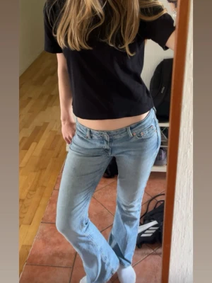 Ljusblå bootcut jeans från Lee - Säljer ett par ljusblå bootcut jeans från junk yard med låg midja och klassisk femficksdesign. Jeansen har en avslappnad passform och är tillverkade i denim med lätt tvättad look. 