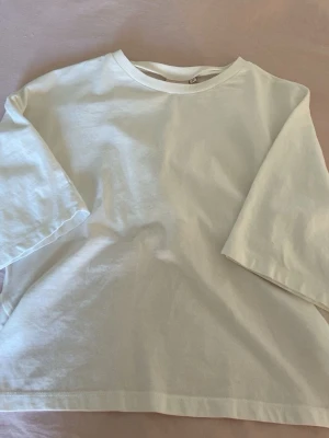 Vit topp med knytband i ryggen ifrån Nelly  - Vit topp med rund halsringning och korta ärmar/ trekvartsarmar. Baksidan har ett snyggt knytband som ger en extra detalj och öppen rygg, ifrån Nelly i storlek xs💓den har en liten fläck på magen men den syns knappt 
