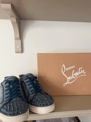 Blåa Christian Louboutin sneakers - Säljer ett par blåa sneakers från Christian Louboutin i mocka med coola nitar på tån. Skorna har vita sulor och matchande blå skosnören. 9/10 skick