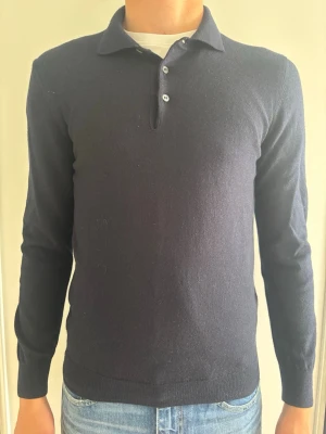 Gran Sasso | 100% Virgin Wool Polo | Made in Italy - Lyxig marinblå stickad pikétröja från italienska Gran Sasso i 100% exklusiv virgin wool. En snygg polo tröja för en sofistikerad stil.  🧵 Märke & Modell: Gran Sasso - Knit Polo 📏 Storlek & Passform: 50 - M (kolla mått nedan) 🧩 Material: 100% Virgin Wool 📐 Mått: Längd 65, Bröst 46, Axel 37, Ärm 64 cm ✅ Skick: 8,5/10 - Fint skick, väl omhändertagen!  ✨ Detaljer: Handgjord kvalitet, pärlemorknappar. 💰 Nypris: Ca 2500 kr ‼️Skickas snabbt‼️