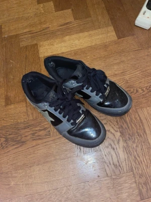 BAPE STA svarta och grå sneakers - Säljer ett par BAPE STA sneakers i svart och grått med den ikoniska stjärnan på sidan. Skorna har svarta skosnören, låg profil och ovandel i glansigt läder. Perfekta för dig som gillar streetwear och vill sticka ut med en klassisk modell.