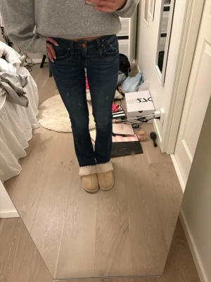 Mörkblå bootcut jeans från LTB - Säljer ett par mörkblå bootcut jeans från LTB med  låg midja. Jeansen har snygga slitningar framtill och kontrastsömmar. Perfekta för dig som gillar en avslappnad men ändå trendig look. De är storlek 24/30 men har sprättat upp de längst ner (jag är cirka 164)!