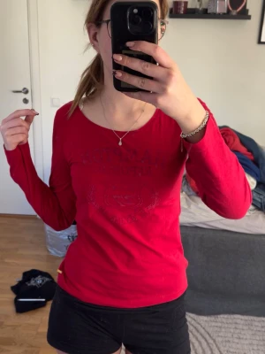 långärmad t-shirt -  Hampton Republic.  - Klassisk röd långärmad t-shirt från Hampton Republic. Toppen har ett snyggt, diskret tryck på bröstet med texten "Hampton Republic N.Y USA" och ett emblem. Mjuk och skon kvalitet med en rundad urringning. Perfekt till jeans för en sportig och fräsch vardagslook! JAG HAR SYTT OMI DEN själv så den passar mer än s/xs men även M beroende på hur man vill att den ska sitta:) • Märke: Hampton Republic. • Storlek: M. Men passar en S/Xs om man vill ha en lite tajtare tröja:) • Detaljer: Tryck på bröstet,