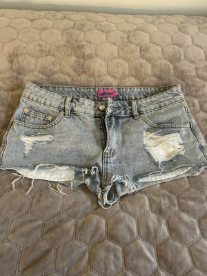 Ljusa denimshorts från Edikted - Säljer ett par ljusa denimshorts från Eclipse med slitna detaljer och fransig kant. Klassisk femficksmodell med knapp och dragkedja framtill.