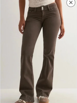 Bruna bootcut jeans med låg midja - Säljer ett par bruna bootcut jeans med låg midja från Nelly. Byxorna är endast använda ett fåtal gånger. De sitter perfekt i längden på mig som är 170