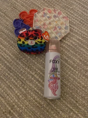 Foxy rosa glitter hårspray - Foxy Hair Color Spray i färgen Pink Glitter. Perfekt för dig som vill ha en tillfällig färgförändring med extra glittereffekt i håret. Sprayen kommer i en smidig metallflaska med rosa detaljer och är enkel att använda för att skapa en cool look.har använt Hårsprejen en gång