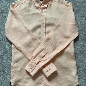 Morris skjorta rosa - Säljer en snygg rosa/aprikos morris skjorta i bra skick. Skjortan är omsydd, avklippt för att vara kortare i längden därav billigt.