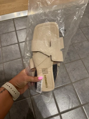 Beige sandaler fr - Snygga beige sandaler från Shein med breda korsade remmar och fyrkantig tå. Tillverkade i ett textilliknande material som ger en clean och modern look. Perfekta för sommaren och lätta att matcha med olika outfits.