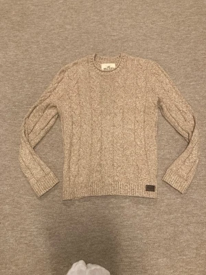 Beige kabelstickad tröja Hollister - Abercrombie & Fitch kabelstickad tröja i mycket bra skick, tröjan är i storlek S och sitter mycket bra över en skjorta eller bara som den är, hör av er om frågor!