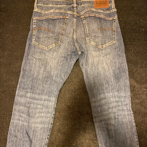 Blå jeans från G-Star RAW - Säljer du dessa fräscha och snygga blå jeans från G-Star RAW med klassisk femficksdesign. Jeansen har raka ben och detaljerade bakfickor med kontrastsömmar. Perfekta för en avslappnad och trendig stil. Storlek är 33/32