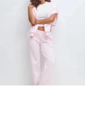 Gina mjukis sett - Mysigt loungewear-set i ljusrosa med vida byxor och matchande tröja. Perfekt för chill dagar hemma. Tillverkad i mjukt material för extra komfort och avslappnad stil.
