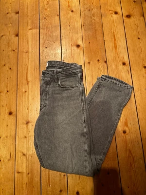 Grå raka jeans från Jack and Jones - Tjena, säljer ett par Jack and Jones jeans med storleken 27w, 30l. Jag säljer jeansen, eftersom de är lite för små för mig runt midjan och jag är 175cm och väger 65 kilo ungefär. Jeansen har hög midja och är tillverkade i ett mjukt bomullstyg med lite stretch. Perfekta för en avslappnad och trendig look. Om du är intresserad är det bara att skriva, och priset är inte hugget i sten!