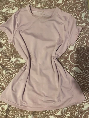 Ljusrosa t-shirt från H&M Move - Säljer en ljusrosa t-shirt från H&M Move med rund halsringning och korta ärmar. Tillverkad i ett mjukt och stretchigt material som passar perfekt till träning eller chill. Enkel och stilren design utan mönster eller tryck.