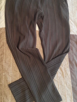 varm och tjock svart kostymbyxor - Snygga och varm kostymbyxor i grått med tunna vertikala ränder. Byxorna har raka ben och dekorativa knappar vid fickan. Perfekta för en stilren och trendig look. Materialet känns mjukt och följsamt.Utan storlek label, men mått på bilder. I tror det är storlek XL.