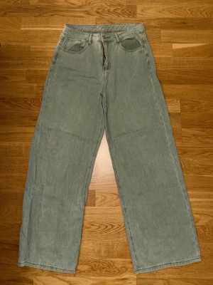 Gröna wide leg jeans från SHEIN - Snygga gröna jeans från SHEIN med wide leg-passform och hög midja. Jeansen har klassiska fickor fram och bak samt knapp- och dragkedjestängning. Perfekta för en avslappnad och trendig stil. Materialet är denim.