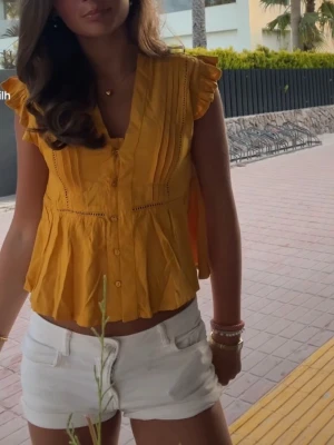 Gul blus med volangärm från LDN - Snygg gul blus från LDN med v-ringning, knappar framtill och volangdetaljer vid ärmslut. Storlek Xs💛💛💛