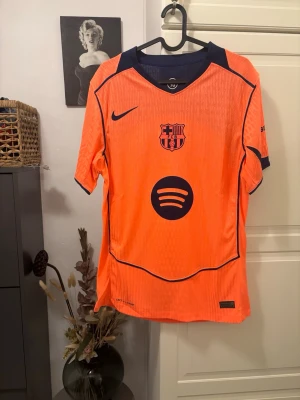 Orange FC Barcelona matchtröja Nike - Säljer en orange FC Barcelona matchtröja från Nike med mörkblå detaljer och logga. Tröjan har Spotify-loggan på bröstet och klubbemblem. Materialet är lätt och andas, perfekt för sport och träning. PLAYER VERSION
