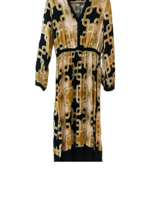 Richard Allen X H&M klänning  - Snygg långklänning från H&M i samarbete med Richard Allen. Klänning med grafiskt mönster i svart, beige och guldtoner. Klänningen har v-ringning, långa ärmar och markerad midja. Perfekt för dig som gillar lite ”businessatyle” vibbar och vill sticka ut. Aldrig använd och i nyskick! Går självklart att diskutera pris☺️