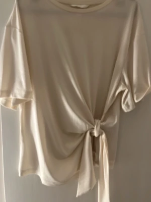 Krämvit topp med knyt framtill - Blus ifrån hm i storlek M, använder den knappast. Väldigt basic och fin. 
