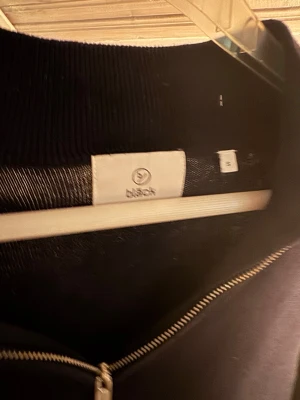Mörkblå stickad tröja med halvzip - Snygg mörkblå stickad tröja från Bläck med halvzip och hög krage. Tröjan har långa ärmar och en stilren design som passar perfekt till jeans Ribbstickad vid halsen för extra komfort.