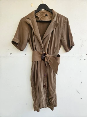 Silkesklänning - Jättefin klänning från Korea i 100% silke. Skulle säga den passar storlek S. Knäpps med knappar nedtill och med brett skärp runt midjan. På två ställen väldigt små hål som man ser på bild 6-7.