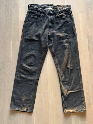 Mörkgrå loose jeans från Vailent - Säljer ett par mörkgrå loose jeans från Vailent med klassisk femficksmodell och knappgylf. Jeansen har en modern look och är tillverkade i kraftigt denimtyg.