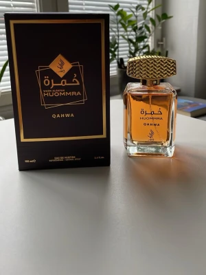 Huommra Qahwa Eau de Parfum 100 ml - Exklusiv parfym från Huommra, Qahwa, i en elegant glasflaska med guldmönstrad kork. Doften kommer i en lyxig svart och guld kartong. Flaskan rymmer 100 ml och har en varm bärnstensfärgad vätska. Perfekt för dig som gillar unika och orientaliska dofter.