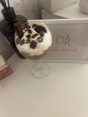 Dekorativ desert doftljus  - Säljer en dekorativ doftljus utformad som en dessert med vispad grädde och chokladbitar på toppen. Perfekt som rolig inredningsdetalj eller present till någon som älskar sötsaker.