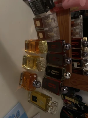 Mix av exklusiva parfymer - Säljer ett set med flera parfymer i olika former och färger. Flera flaskor har guld- eller silverfärgade detaljer och eleganta lock. Märken som Oud Mood och You finns med. Flaskorna är genomskinliga och visar vätska i bärnstens- och guldfärgade toner.