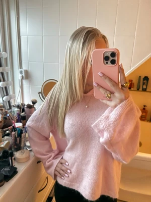 Ljusrosa stickad tröja med luva ifrån Gina tricot  - Mysig ljusrosa stickad tröja med v-ringad hals och långa ärmar. Tröjan har en avslappnad passform och ribbstickade muddar vid ärmslut och nederkant. Tröjan har ett litet håll men annars är den helt oanvänd.