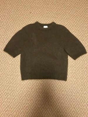 Mörkgrön stickad tröja kort ärm - En enkel och stilren mörkgrön stickad tröja med korta ärmar och rund hals. Tröjan har en boxig passform. Perfekt för lager på lager och passar till det mesta. 💚💚