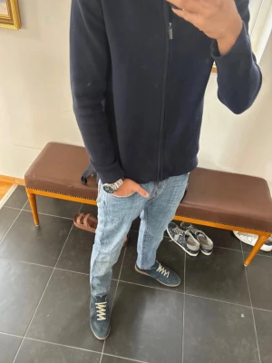 Ljusblå jeans från Jacob Cohen - Säljer ett par ljusblå jeans från Jacob Cohen med klassisk femficksmodell och raka ben. Jeansen har kontrastsömmar och en beige patch med logga bak i midjan. Tillverkade i mjukt denimtyg som ger en avslappnad look.