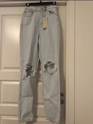 Ljusblå ripped jeans från don’t think twice - Säljer ett par nya ljusblå mom jeans från don’t think twice med stora slitningar över båda knäna. Jeansen har hög midja, raka ben. W34L32